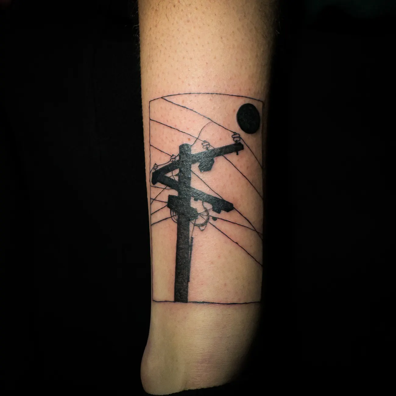 Tatuaje de un poste de luz y cables encuadrados en un rectángulo